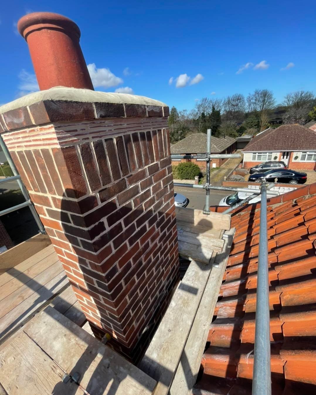 Brick chimney rebuilt above a clay tiled roof