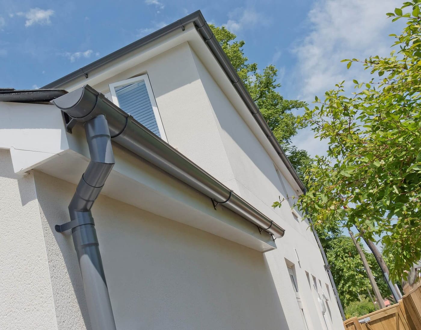 Dark grey guttering and downpipe on a white rendered house