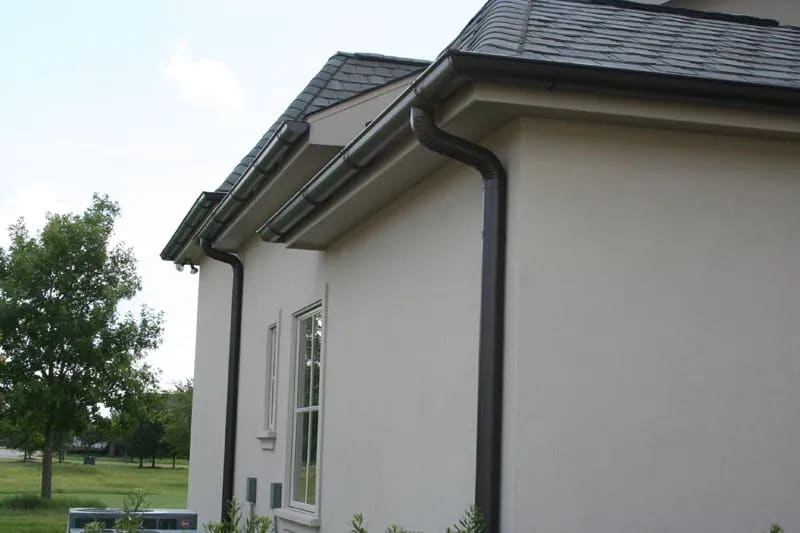 Guttering and downpipes on a rendered house beside a park
