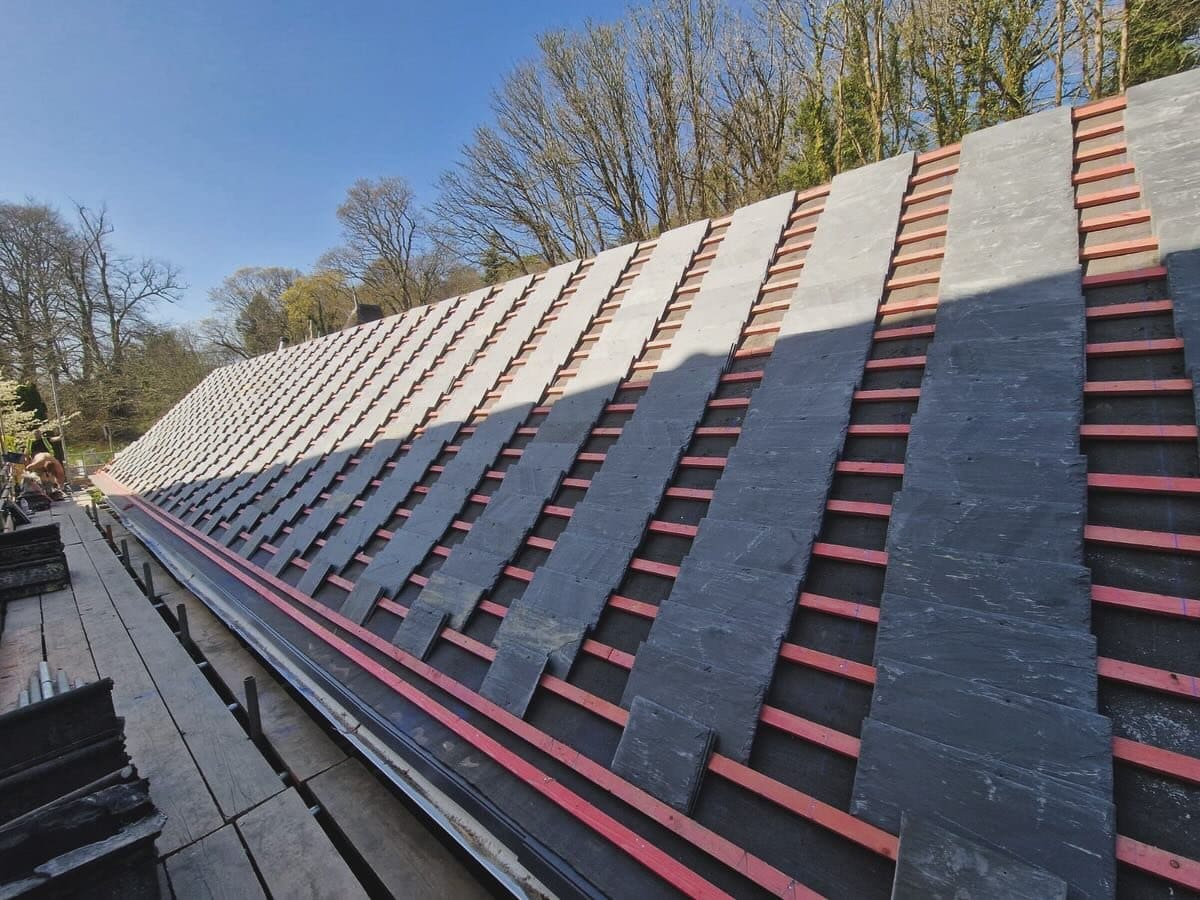 Slate roof being laid over new battens, with courses half complete